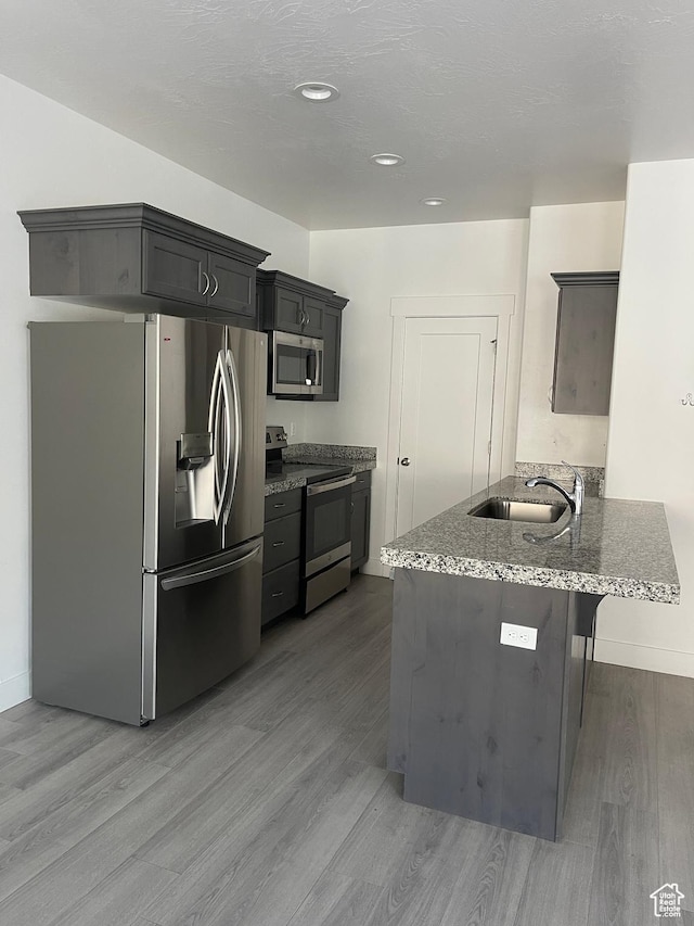 4937 E Lake Dr, Eagle Mountain, UT 84005 - kitchen featuring stone countertops, a sink, light wood-style floors, and appliances with stainless steel finishes