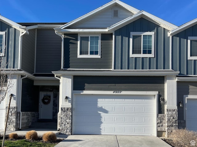 4937 E Lake Dr, Eagle Mountain, UT 84005 - view of front facade with board and batten siding, stone siding, a garage, and concrete driveway