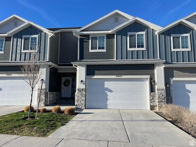 view of front of house featuring stone siding, an attached garage, board and batten siding, and driveway