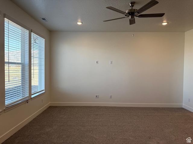 spare room featuring a textured ceiling, visible vents, carpet, baseboards, and a ceiling fan