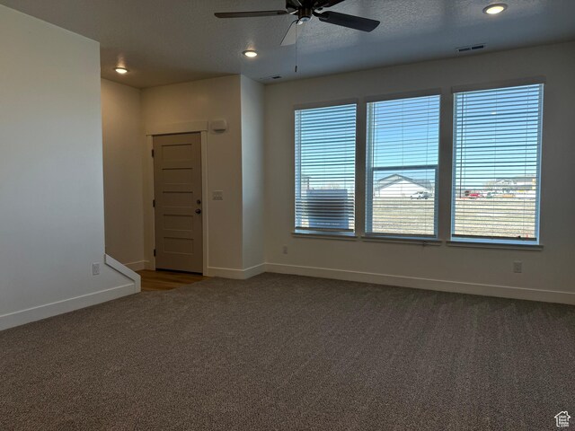 carpeted empty room featuring baseboards, ceiling fan, visible vents, and a wealth of natural light