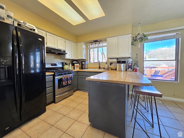 243 Downs Cir, Ogden, UT 84404 - kitchen featuring a peninsula, gas stove, under cabinet range hood, white cabinetry, and black fridge