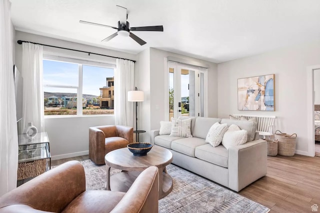 living room with a ceiling fan, baseboards, a healthy amount of sunlight, and wood finished floors
