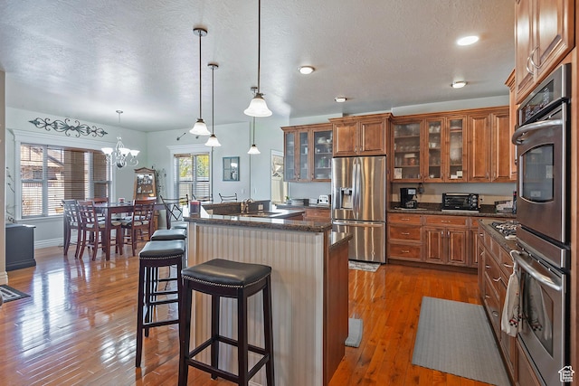 3173 N 1050 W, Pleasant View, UT 84414 - kitchen featuring a kitchen bar, dark wood-style floors, brown cabinets, and appliances with stainless steel finishes