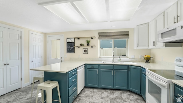 kitchen featuring light countertops, a breakfast bar, a peninsula, white appliances, and white cabinets