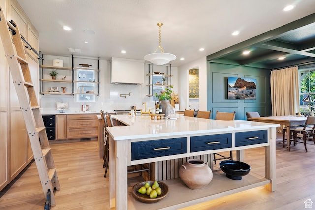 kitchen featuring a kitchen island with sink, light countertops, light wood-style floors, and open shelves