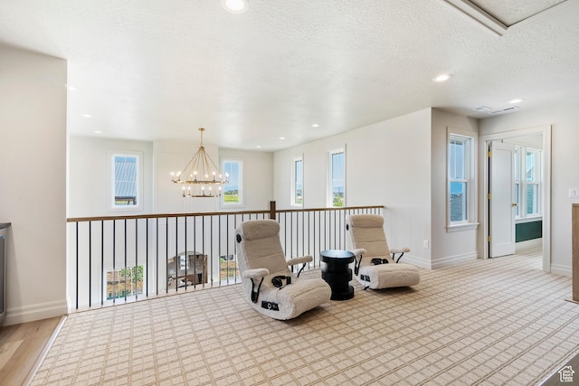 living area featuring baseboards, a textured ceiling, recessed lighting, and an inviting chandelier