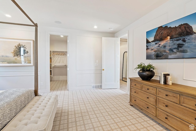 bedroom with recessed lighting, a decorative wall, visible vents, and a spacious closet
