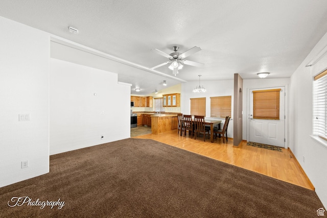 180 N 1100 E Unit 165, Washington, UT 84780 - unfurnished living room featuring light colored carpet, a sink, lofted ceiling, ceiling fan with notable chandelier, and light wood-style floors