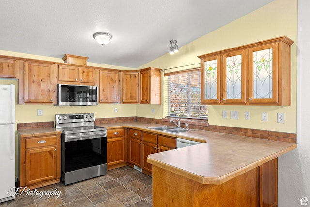 180 N 1100 E Unit 165, Washington, UT 84780 - kitchen with a peninsula, appliances with stainless steel finishes, a sink, vaulted ceiling, and brown cabinetry