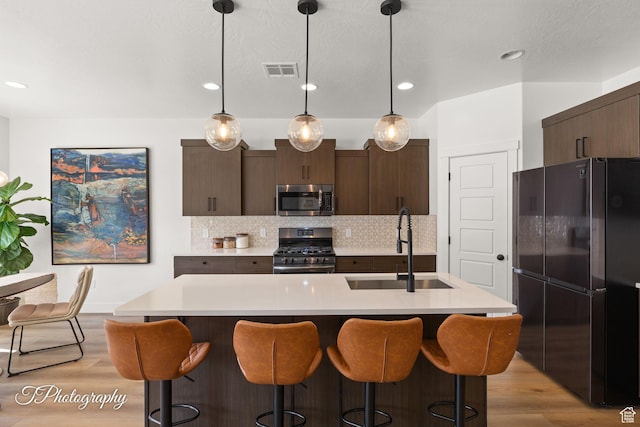 kitchen featuring light countertops, tasteful backsplash, stainless steel appliances, a sink, and visible vents