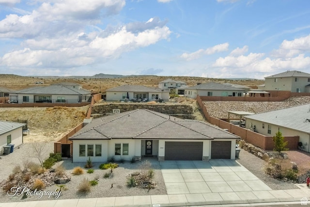 view of front of property with fence, an attached garage, concrete driveway, a tile roof, and a residential view