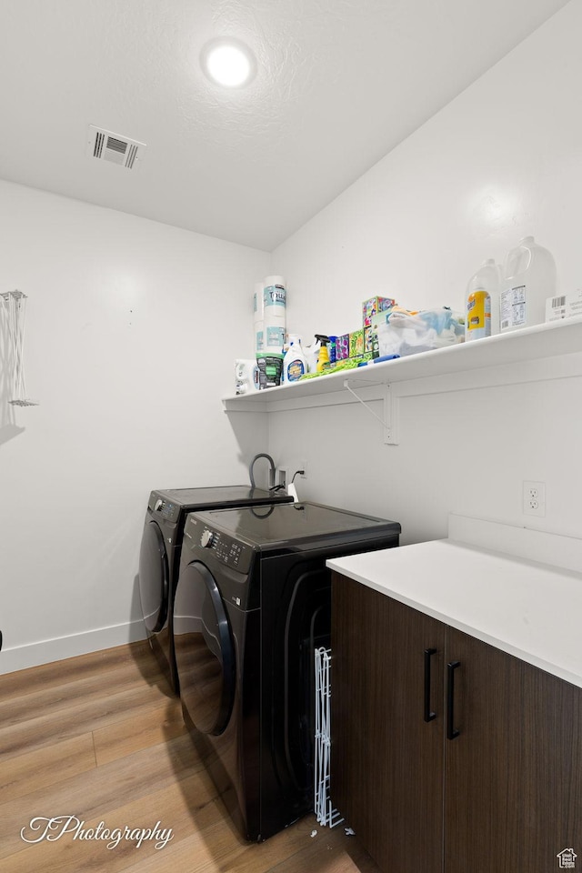 washroom with baseboards, separate washer and dryer, light wood finished floors, visible vents, and laundry area