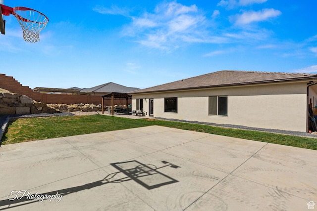rear view of property featuring a tile roof, stucco siding, fence, a patio, and a lawn
