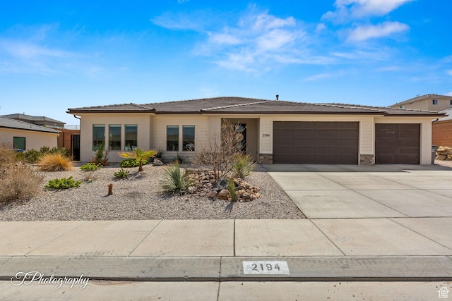 prairie-style home featuring stone siding, concrete driveway, and an attached garage