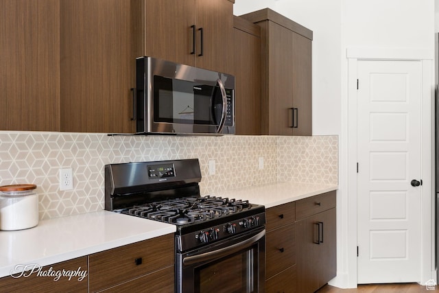 kitchen with light countertops, stainless steel microwave, range with gas stovetop, and tasteful backsplash