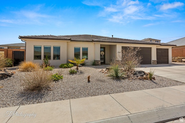 prairie-style house with a tile roof, stucco siding, an attached garage, and concrete driveway