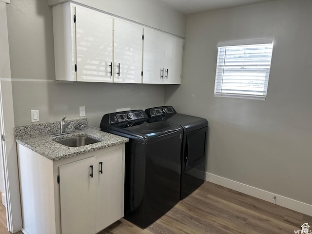 laundry area featuring washing machine and dryer, wood finished floors, cabinet space, and baseboards