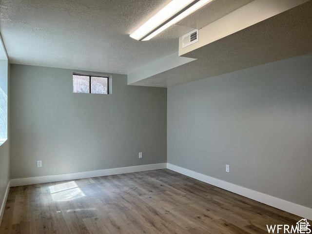 basement with a textured ceiling, wood finished floors, and baseboards