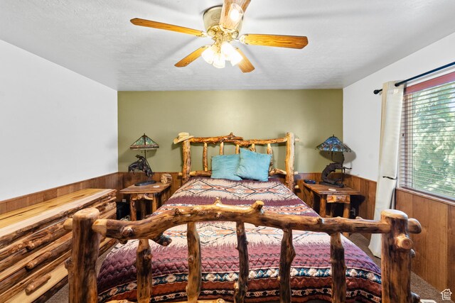 18509 Jefferson Ave, Eagle Mountain, UT 84013 - carpeted bedroom featuring wainscoting, wood walls, a ceiling fan, and a textured ceiling