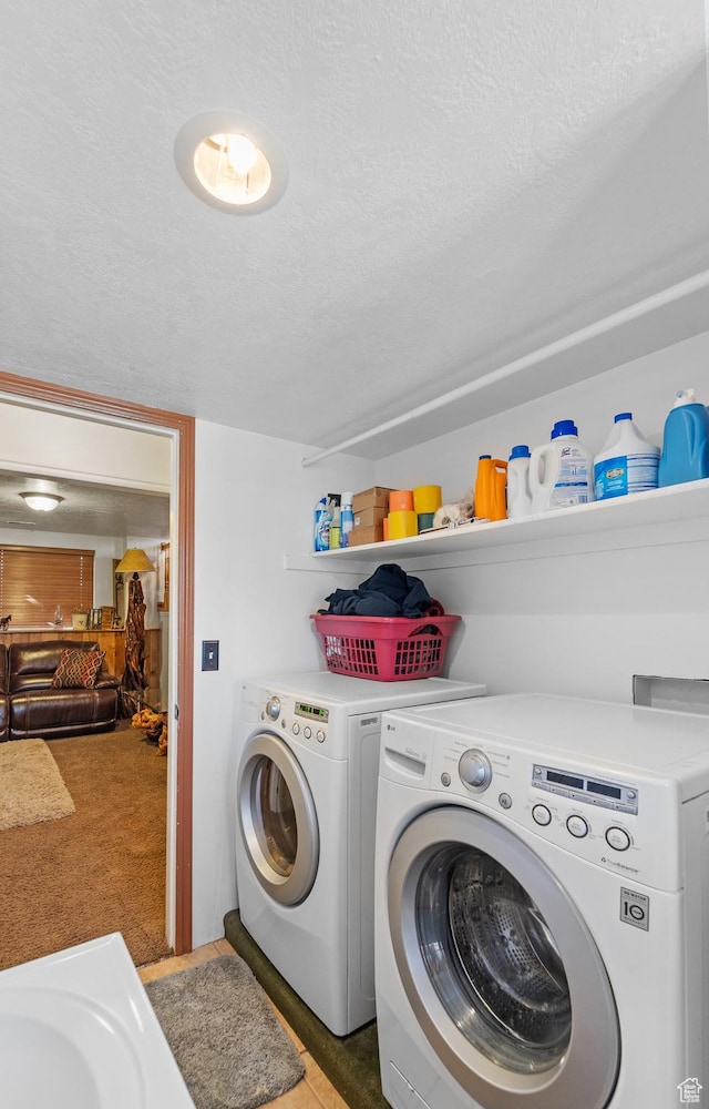 clothes washing area with laundry area, separate washer and dryer, and a textured ceiling
