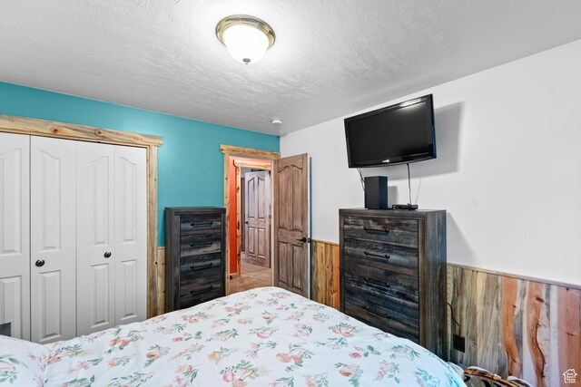 18509 Jefferson Ave, Eagle Mountain, UT 84013 - bedroom featuring a wainscoted wall, wooden walls, a closet, and a textured ceiling