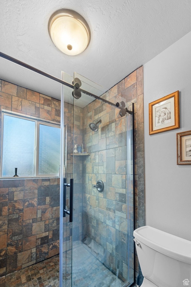 bathroom featuring a stall shower, toilet, and a textured ceiling