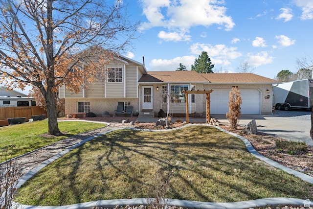 split level home featuring driveway, a front yard, an attached garage, fence, and brick siding