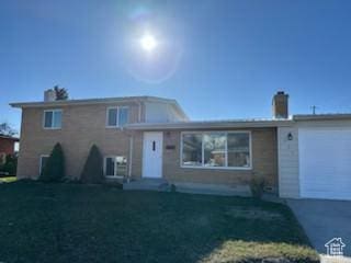 tri-level home featuring a front lawn and an attached garage