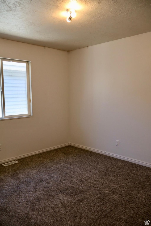 carpeted spare room with a textured ceiling and baseboards