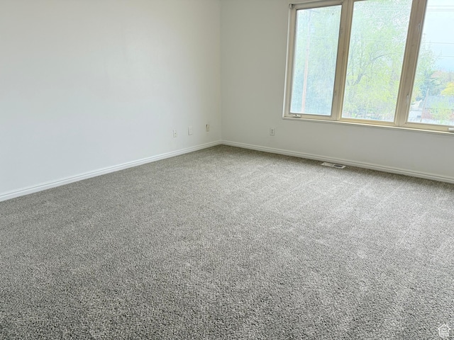 carpeted empty room featuring plenty of natural light and baseboards