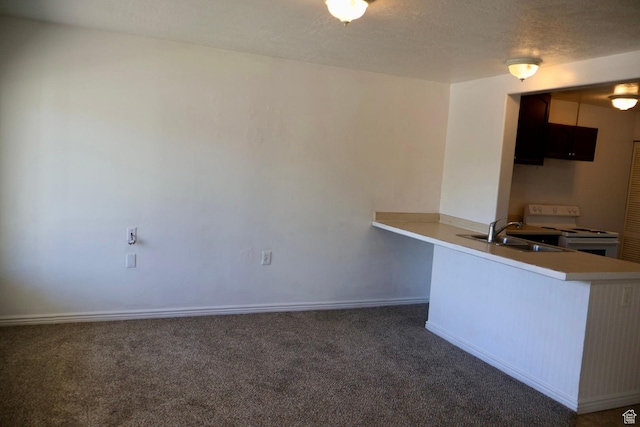 kitchen with a sink, white range with electric cooktop, carpet flooring, a peninsula, and baseboards