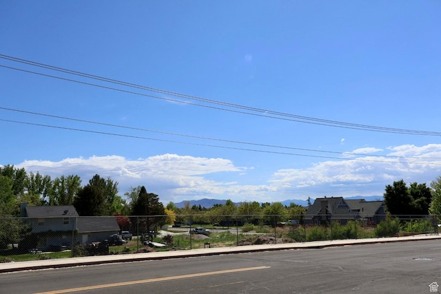 view of asphalt street featuring curbs, sidewalks, and a mountain view