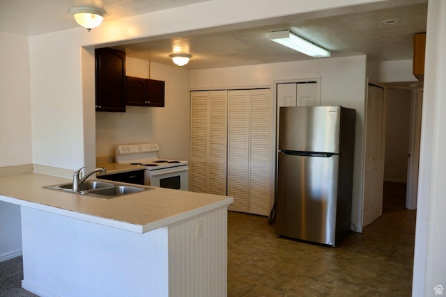 kitchen with freestanding refrigerator, white electric stove, a sink, a peninsula, and light countertops