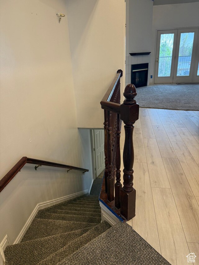 stairs featuring wood finished floors, baseboards, and a fireplace
