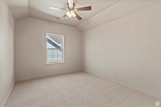 spare room with ceiling fan, vaulted ceiling, baseboards, and light carpet