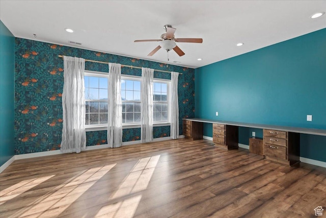 interior space with baseboards, built in study area, ceiling fan, and wallpapered walls