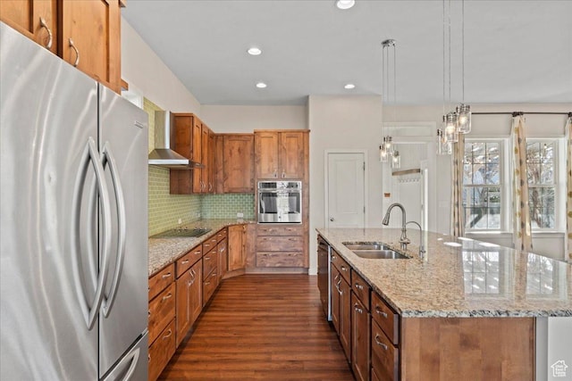 kitchen featuring wall chimney exhaust hood, stainless steel appliances, a sink, dark wood finished floors, and brown cabinetry