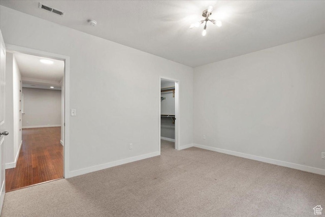 unfurnished bedroom with carpet flooring, visible vents, baseboards, a closet, and a walk in closet