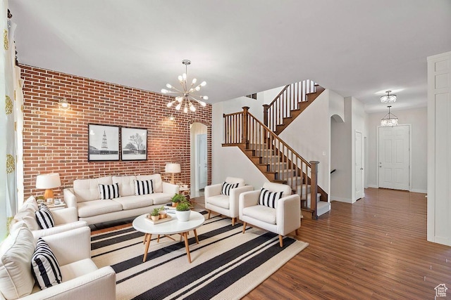living room featuring stairway, brick wall, arched walkways, and a notable chandelier