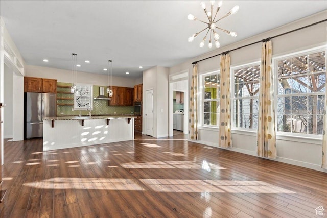 unfurnished living room with a sink, a chandelier, washer / dryer, french doors, and dark wood-style floors