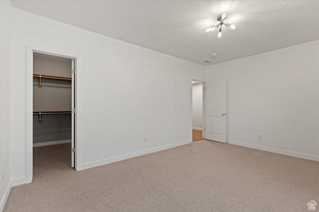 unfurnished bedroom with light colored carpet, baseboards, and a spacious closet