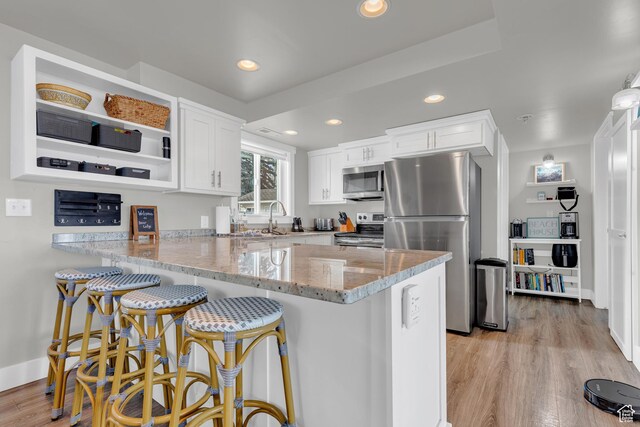 660 S Bear Lake Blvd, Garden City, UT 84028 - kitchen with stainless steel appliances, a peninsula, light stone countertops, white cabinets, and recessed lighting
