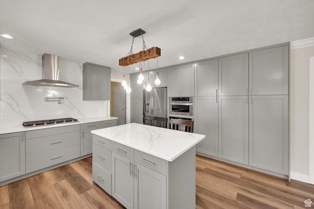 1867 E Indian Ln, Layton, UT 84040 - kitchen featuring gray cabinetry, wall chimney exhaust hood, stainless steel appliances, tasteful backsplash, and light wood-style flooring