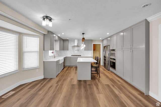 1867 E Indian Ln, Layton, UT 84040 - kitchen featuring gray cabinetry, stainless steel refrigerator with ice dispenser, a kitchen bar, light wood-type flooring, and light countertops