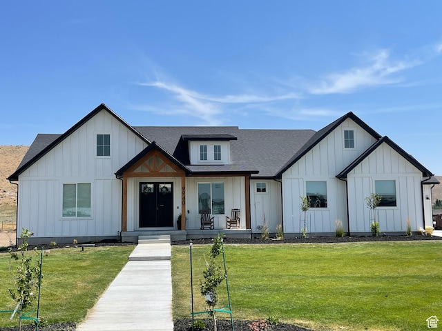 modern farmhouse featuring a shingled roof, board and batten siding, covered porch, and a front yard