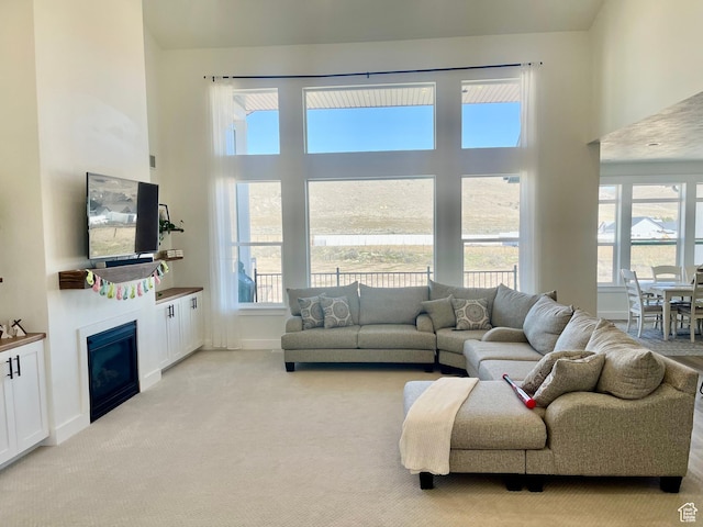 9940 N Vande Way, Eagle Mountain, UT 84005 - living room featuring light carpet, a towering ceiling, a glass covered fireplace, and a healthy amount of sunlight
