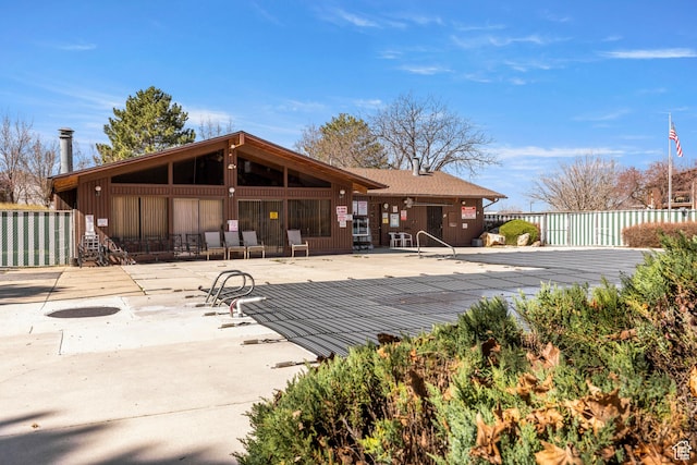 rear view of property featuring fence, a patio area, and a community pool