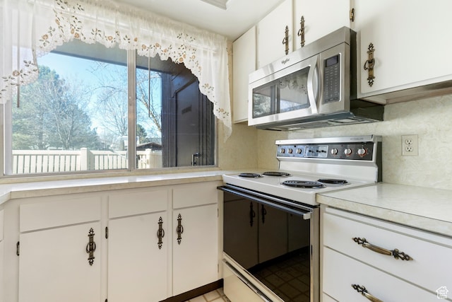 kitchen with stainless steel microwave, light countertops, plenty of natural light, and range with electric cooktop