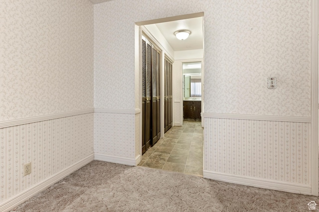 corridor with wallpapered walls, carpet floors, and wainscoting
